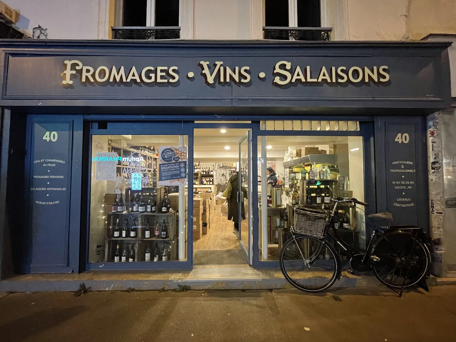 La devanture des Établissements Moots au 40 rue Popincourt, éclairée le soir