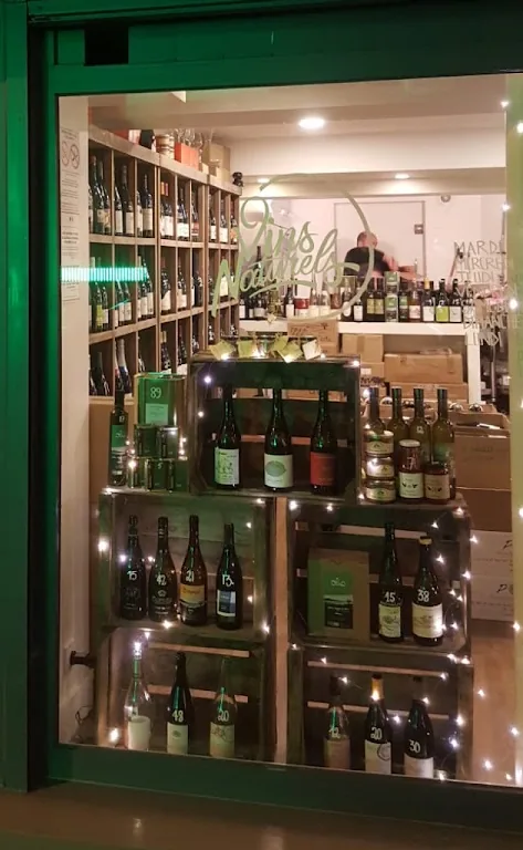 La vitrine de la boutique le soir, bouteilles disposées dans des caisses en bois et guirlande lumineuse